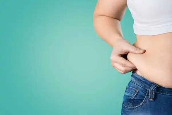 Image of woman pinching her love handles to show weight gain Paisley